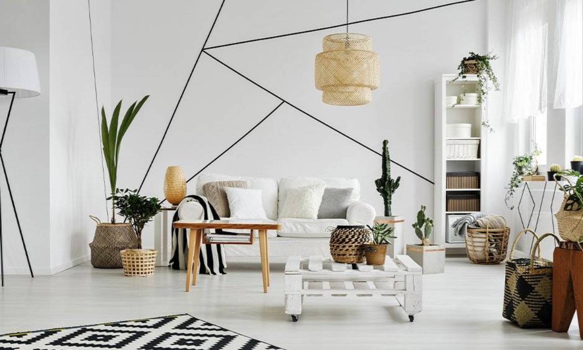 Modern living room with white furniture, geometric wall patterns, and natural decor elements like plants and wicker baskets.