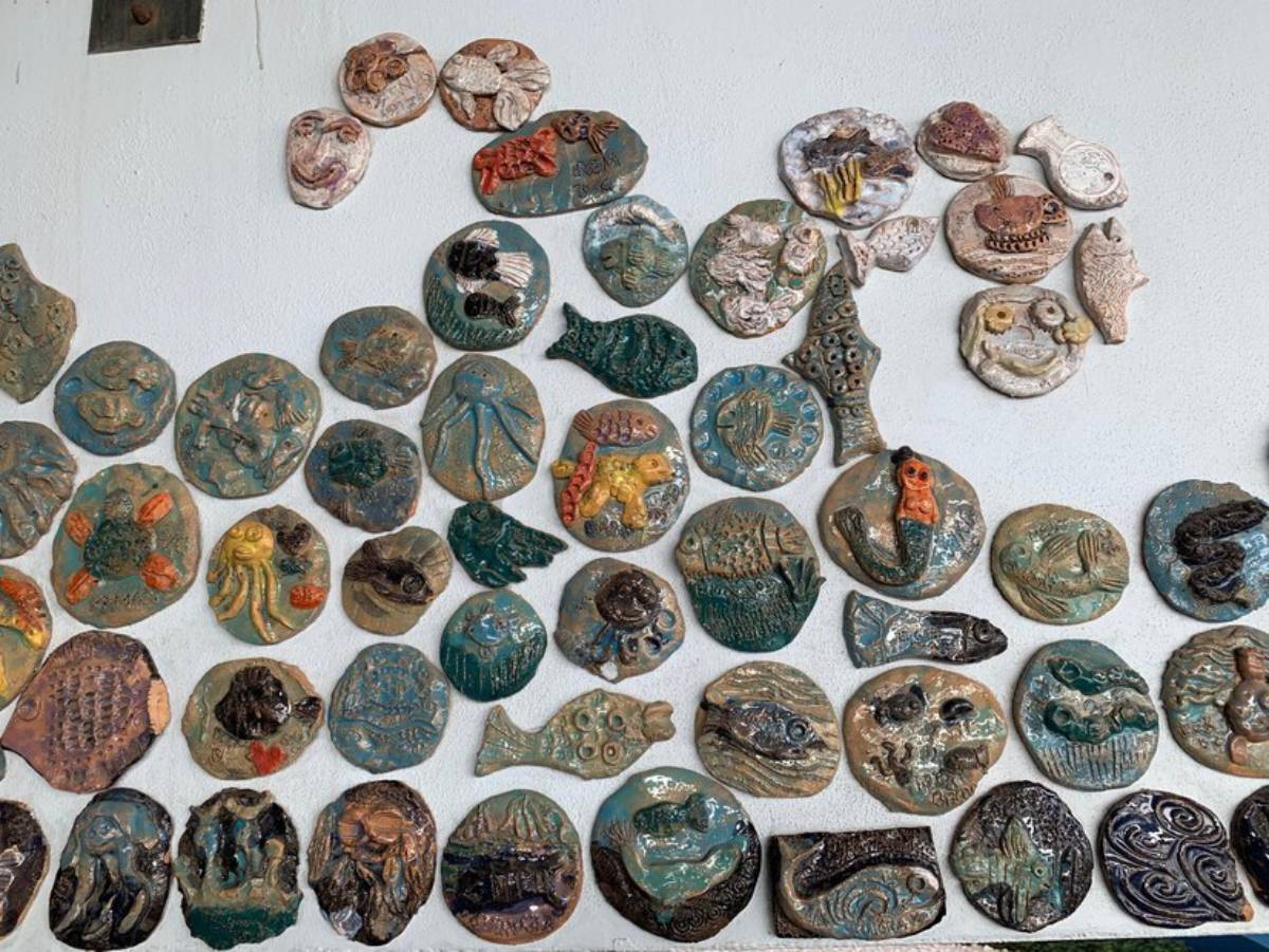 An assortment of colorful ceramic plaques with varying ocean-themed designs mounted on a white wall.