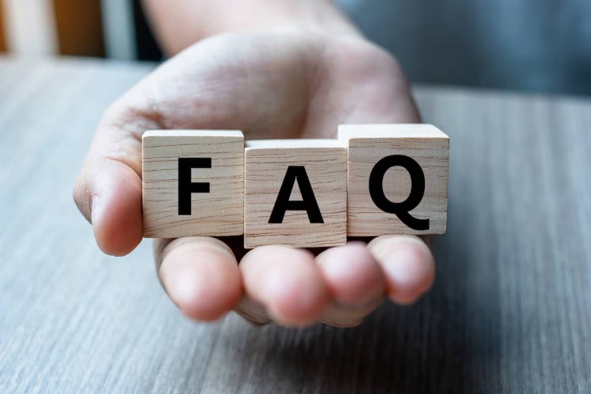 A hand holding wooden blocks spelling FAQ.