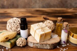 Natural soap bars, essential oil bottles, and bath accessories on a wooden background.