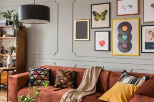 Cozy living room with a brown velvet sofa, colorful pillows, and a wall of framed art.