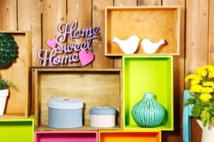 Colorful home decor display on wooden wall with boxes, a "Home Sweet Home" sign, and decorative items.